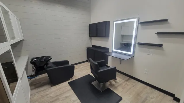 An interior suite with shiplap walls, styling chair, shampoo bowl, and lit mirror
