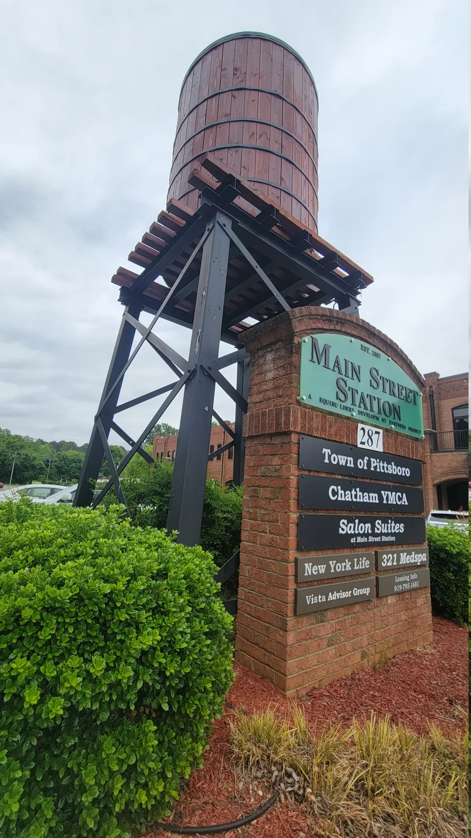 The wooden water tower and brick sign at Main Street Station, 287 East Street, with Salon Suites listed among the businesses inside