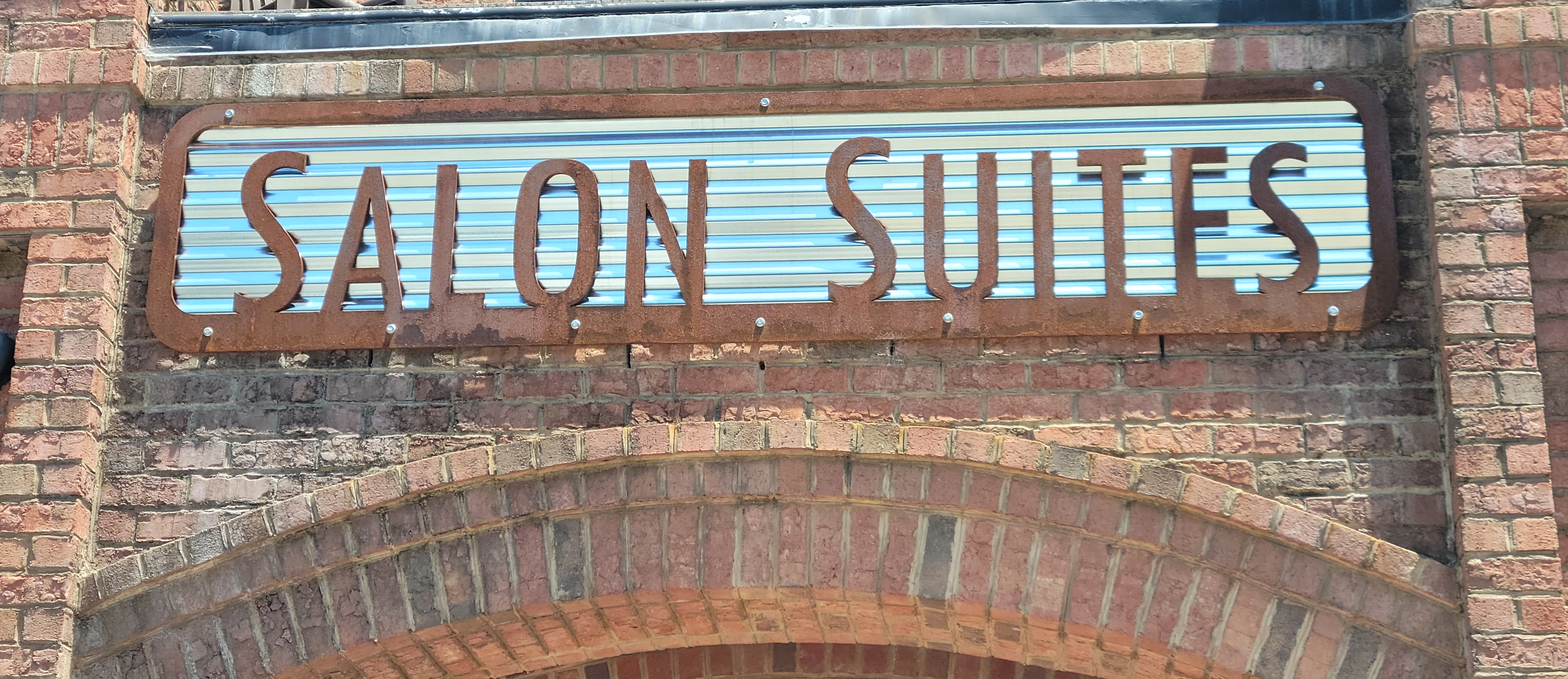 The Salon Suites at Main Street Station sign on the building's historic brick facade