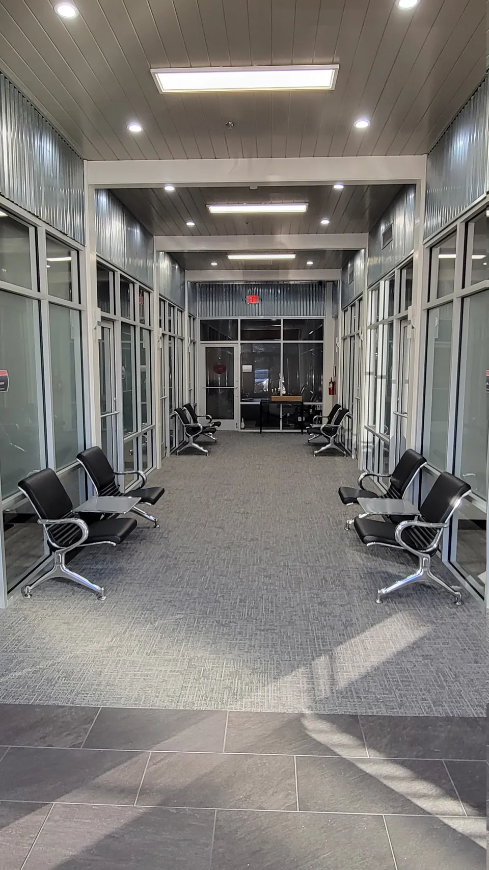 The indoor hallway at Salon Suites, with glass-fronted suites on both sides and seating for waiting clients